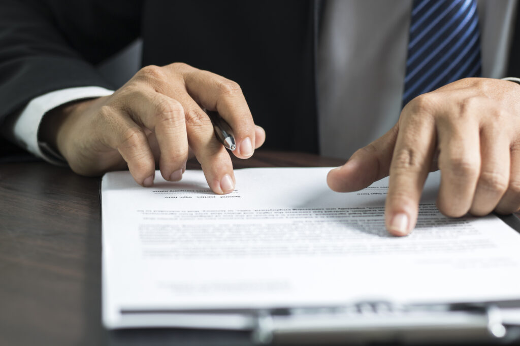 Persona leyendo contrato y firmándolo con bolígrafo