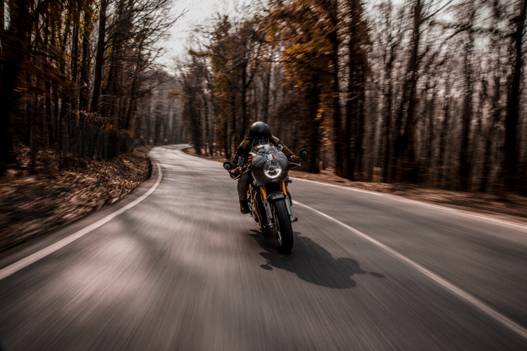 Moto circulando por carretera con árboles